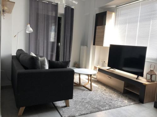 a living room with a black couch and a flat screen tv at Gtrip Gazi Duplex Apartment - 33701 in Athens