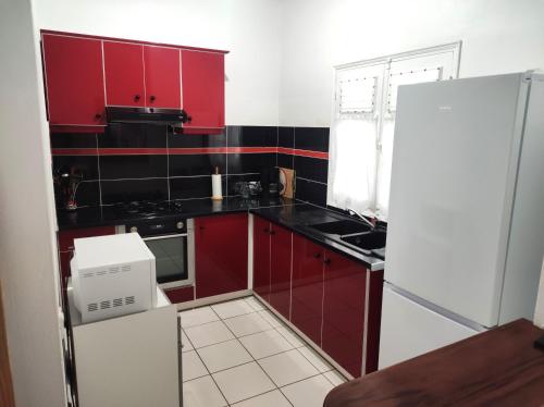 a small kitchen with red cabinets and a refrigerator at Agréable maison 3 pièces tout confort pour 4 personnes - Vue sur jardin in Saint-François
