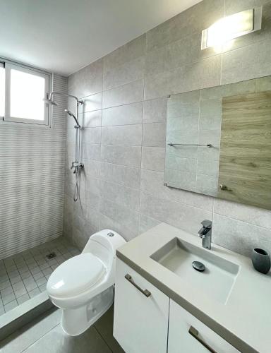 a white bathroom with a toilet and a sink at Signature Point Bella Vista, Sea View 2 BR in Panama City