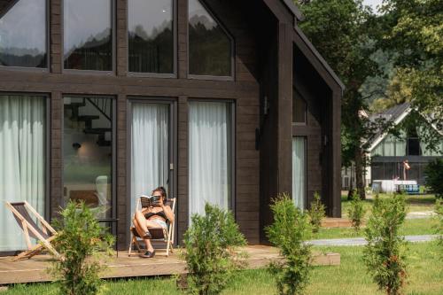 a woman sitting in a chair on the porch of a house at Caryńska Resort & SPA in Lutowiska