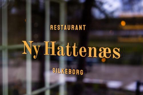 a window with the words restaurant n kitchens in gold letters at Hotel Ny Hattenæs in Silkeborg