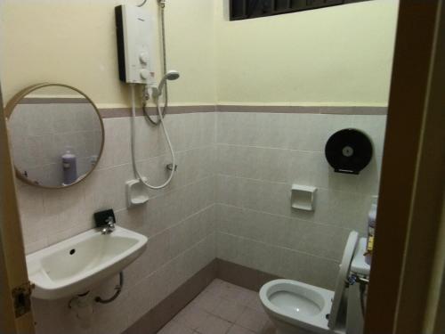 a bathroom with a sink and a toilet and a mirror at Pinang Beach Home @ Ferringhi in Batu Ferringhi