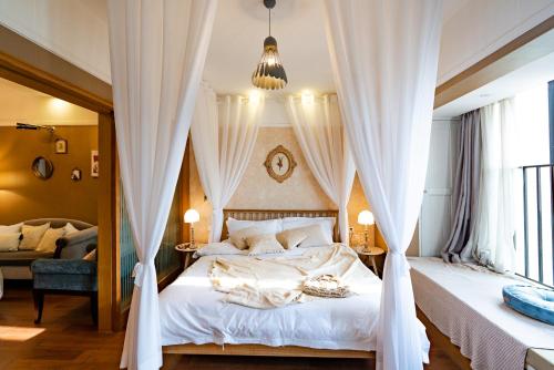 a bedroom with a canopy bed with white curtains at Chongqing Forest Design B&B in Chongqing