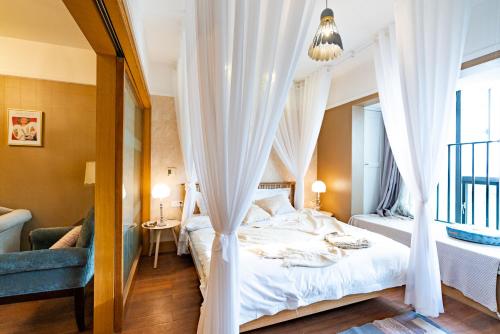 a bedroom with a bed with white curtains at Chongqing Forest Design B&B in Chongqing