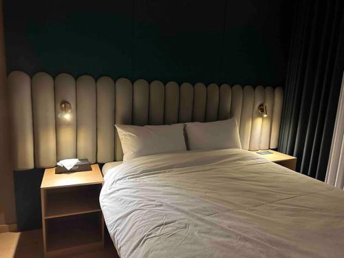 1 dormitorio con 1 cama blanca grande y pared verde en Gunamro Hotplace, en Busan