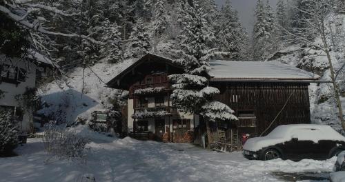 ein schneebedecktes Haus mit einem davor geparkt in der Unterkunft Auf der Tannermühle in Bayrischzell