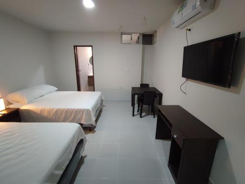 a hotel room with two beds and a flat screen tv at Amaca Hostal in Santa Cruz de la Sierra