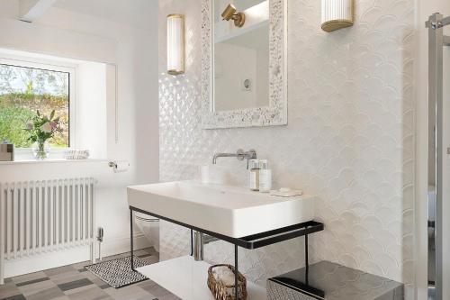 uma casa de banho com um lavatório branco e um espelho. em The Lodge em Strete