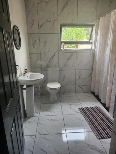 a bathroom with a toilet and a sink and a window at Ezcel accommodation in Cape Town