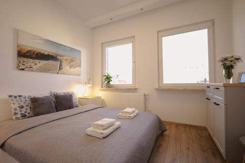 a bedroom with two towels on a bed with two windows at Apartament w sercu Swinoujscia z 3 sypialniami in Świnoujście