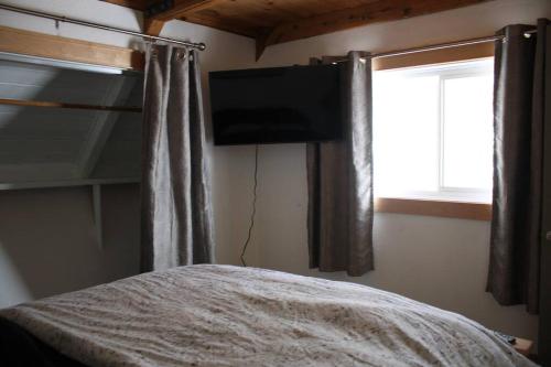 a bedroom with a bed and a television and a window at Rustic A-Frame hot tub retreat near Deception Pass in Oak Harbor
