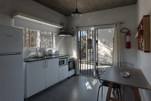 uma cozinha com armários brancos, uma mesa e uma janela em Complejo il Pensiero Punta del Diablo em Punta Del Diablo