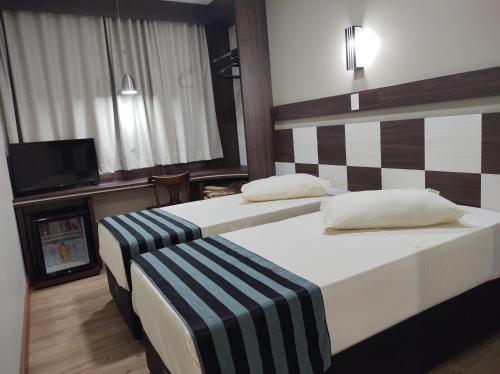 a hotel room with two beds and a television at Hotel Maestro Express in Francisco Beltrão