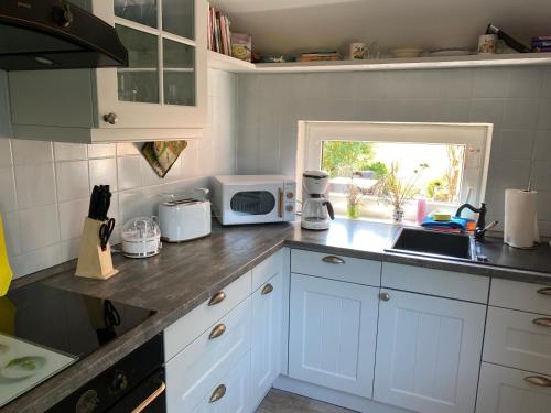 una cucina con mobili bianchi e un piano di lavoro di Ferienhaus Astrid 25196 a Bunde
