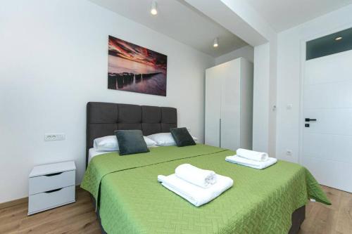 - une chambre avec un lit vert et 2 serviettes dans l'établissement Villa Olea, à Zmijavci