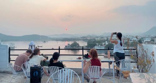 a group of people sitting on a balcony taking pictures of the water at Tamasha Udaipur in Udaipur