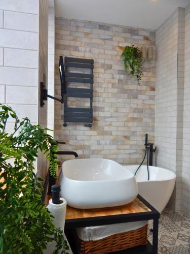a bathroom with a white tub and a sink at DJH Homes - Luxurious and chic 3BR Grade II Industrial House with log burner and electric blinds - JQ, Birmingham City in Birmingham