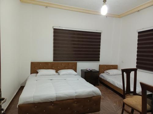 Un dormitorio con 2 camas y una silla. en Ruins Hotel Jerash en Jarash