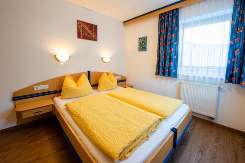 1 dormitorio con 1 cama con sábanas amarillas y ventana en Apartment Bacher Nr.2, en Wald im Pinzgau