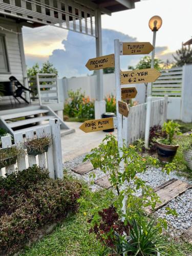a garden with signs pointing to different places at Tok Abah Cottage in Kota Bharu