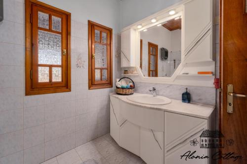 a white bathroom with a sink and a mirror at Alonia Cottage in Episkopí
