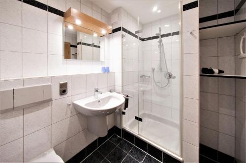 ein weißes Bad mit einem Waschbecken und einer Dusche in der Unterkunft Gästehaus Sonner in Dietmannsried