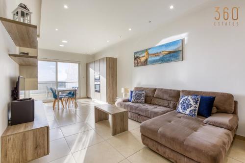 ein Wohnzimmer mit einem Sofa und einem Tisch in der Unterkunft Spacious, designer 2BR home with Captivating Views by 360 Estates in Mellieħa
