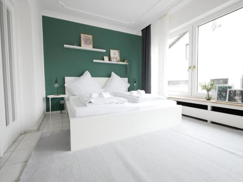um quarto com uma cama branca e uma parede verde em 110 m2, Dachterrasse, Küche, zentral, ruhige Lage em Paderborn