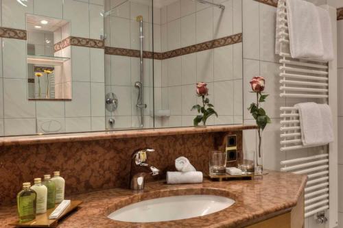 a bathroom with a sink and a large mirror at Hotel zum ERDINGER Weißbräu in Erding