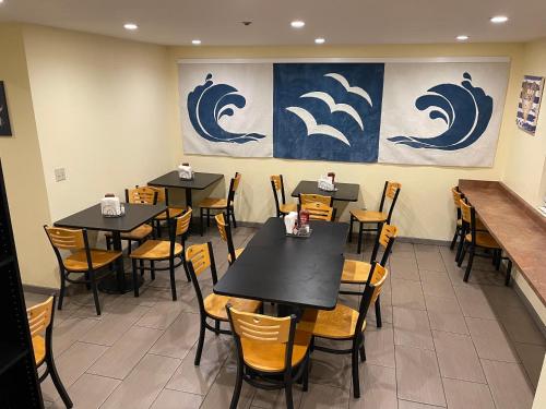 a dining room with tables and chairs and a painting of waves at Seabird Lodge Fort Bragg in Fort Bragg