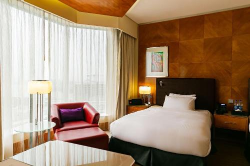 a hotel room with a bed and a red chair at Lagos Continental Hotel in Lagos