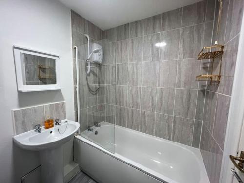 Ideal 2 Bedroom Glasgow Home في غلاسكو: حمام مع حوض أبيض ومغسلة ودش