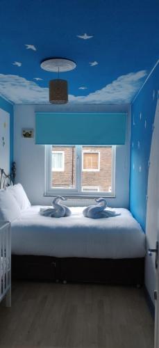 Cette chambre bleue comprend un lit et une fenêtre. dans l'établissement Richmond London 2 bed room Appartement, à Londres