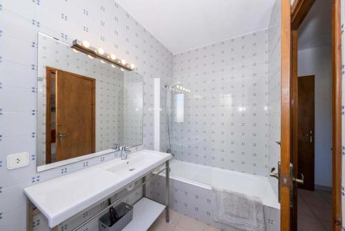 Un baño blanco con lavabo y espejo. en Villa Binibels, en Binibeca