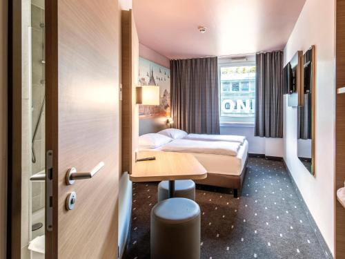 ニュルンベルクにあるB＆B ホテル ニュルンベルク Hbfのベッドとデスクが備わるホテルルームです。