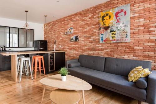 a living room with a couch and a brick wall at Cabana & Appartement type Loft - Bellecour in Lyon