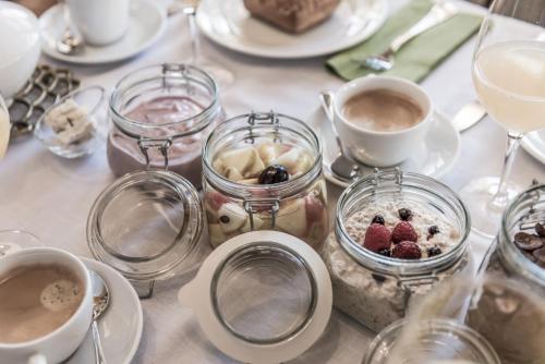 a table with jars of food and cups of coffee at Aadla Walser-Chalets mit privater Sauna, Hotpot und Hotelservice in Schröcken