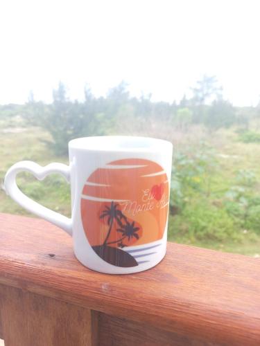 a coffee cup sitting on top of a wooden rail at Mar de Arraial, Suites da Ju in Arraial do Cabo