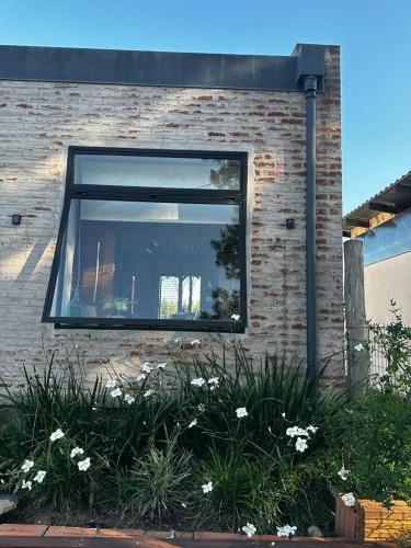 a window on the side of a brick building with white flowers at Casa de los lagos 1 a 8 personas in Rivera