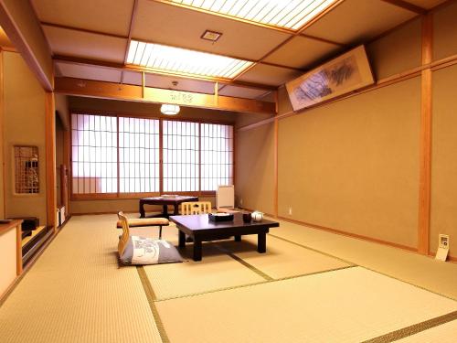 ein Zimmer mit einem Tisch und Stühlen in einem Zimmer in der Unterkunft Sinonomesou in Toyooka