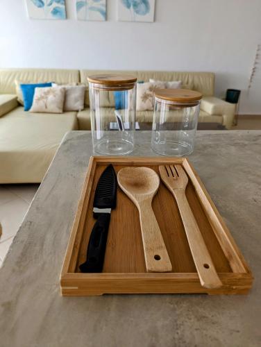 a wooden cutting board with utensils on a table at Tropical Leaves Sea view penthouse ca Greta 2 floor in Sal Rei