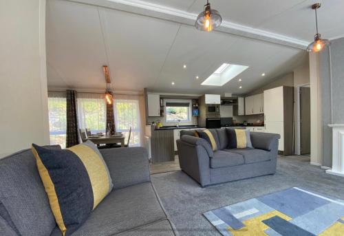 een woonkamer met 2 banken en een keuken bij SL06 - Idwal Lodge with Hot Tub in Bangor