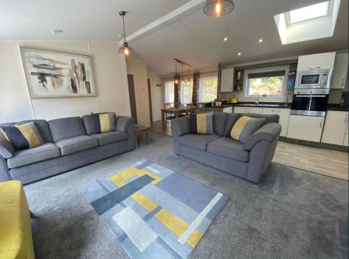 a living room with two couches and a kitchen at SL06 - Idwal Lodge with Hot Tub in Bangor