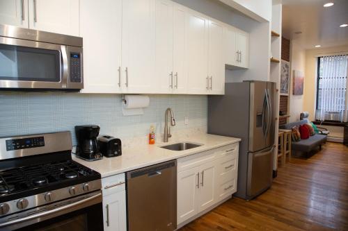 a kitchen with white cabinets and stainless steel appliances at The Harlem Cascades in New York