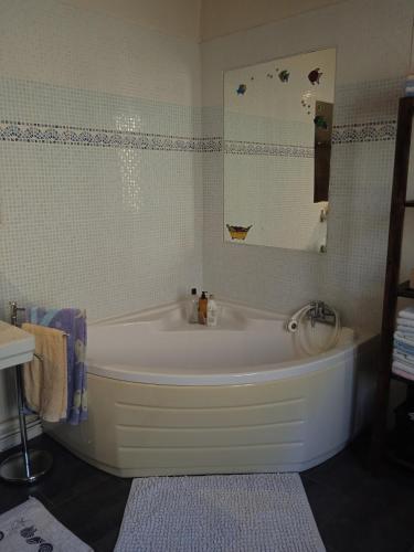 une baignoire blanche dans une salle de bain avec un miroir dans l'établissement Maison de famille à Périgueux, à Périgueux