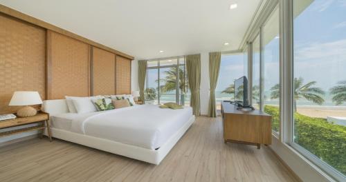 a bedroom with a white bed and a large window at Tolani Le Bayburi Villas, Hua Hin - Pranburi in Pran Buri