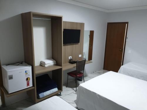 um quarto com 2 camas e uma secretária com um computador em Hotel Rio Paraná em Guaíra