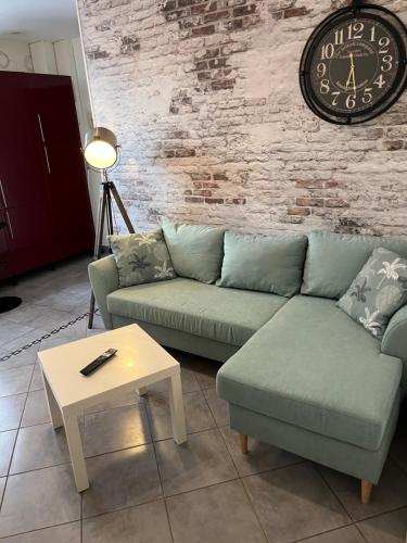 uma sala de estar com um sofá e um relógio na parede em Le Parmentier em Châlons-en-Champagne