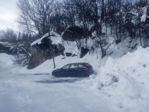 une voiture garée sur une route recouverte de neige dans l'établissement Agréable appartement au calme avec vue montagne, commune de Le Monêtier les Bains - Le Freyssinet, à Les Guibertes