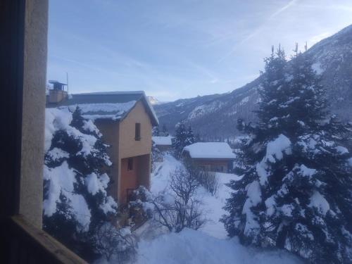 una casa en la nieve con árboles y montañas en Agréable appartement au calme avec vue montagne, commune de Le Monêtier les Bains - Le Freyssinet, en Les Guibertes
